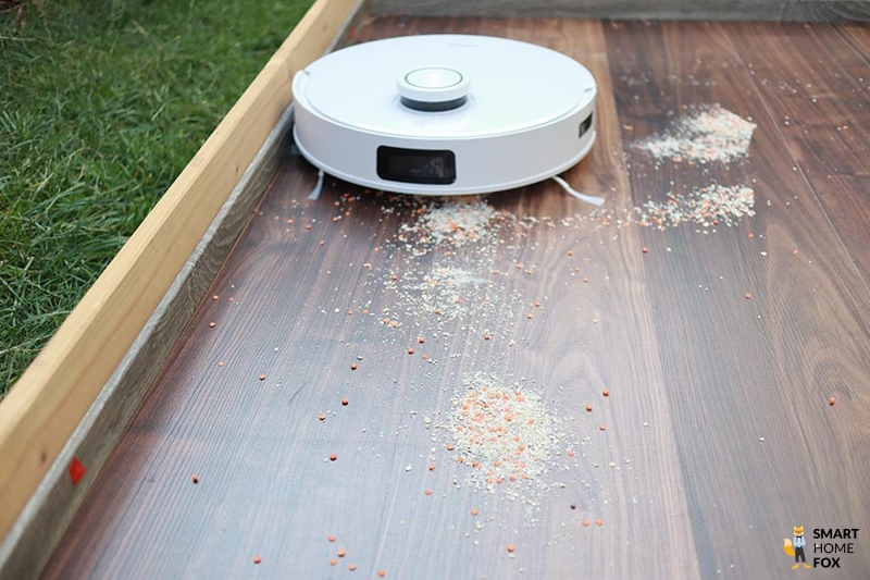 ECOVACS DEEBOT T10 reinigt im Test Haferflocken auf einem Hartboden.